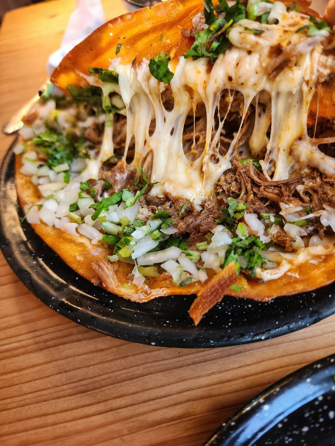 Fotografía gastronómica en primer plano de quesabirria con queso fundido y birria deshebrada