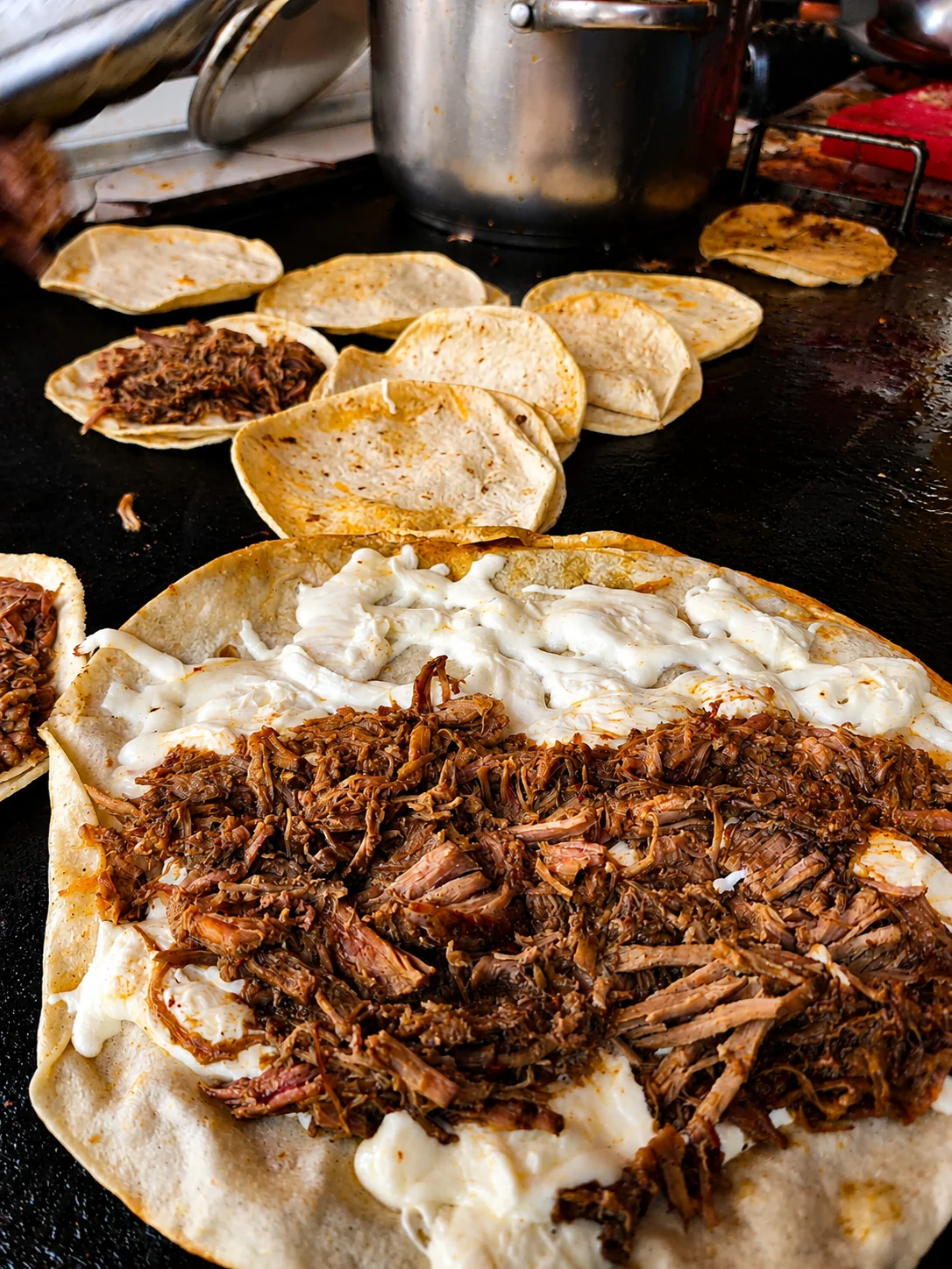 Fotografía detrás de cámaras de birria y tortillas durante la preparación en cocina